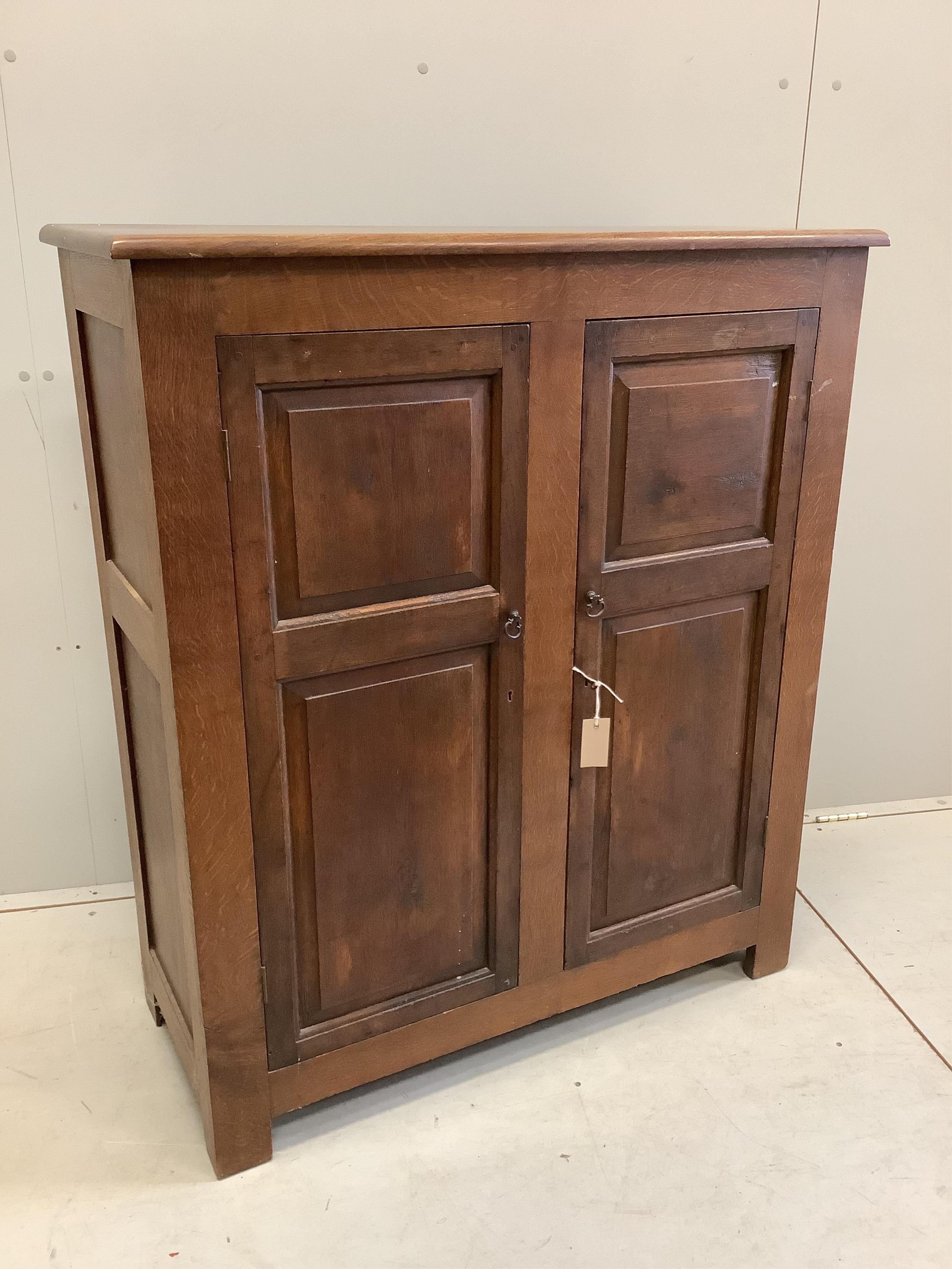 An early 20th century panelled oak two door cupboard, width 96cm, depth 42cm, height 112cm. Condition - fair, top faded, ring and spot stained.